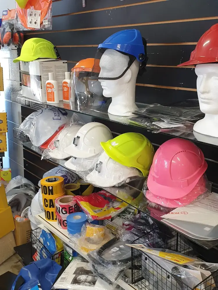Hard hats, safety helmets and PPE gear on shelves at Custom Workwear